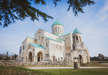 Fototapeta na wymiar Bagrati Kutaisi cathedral with no poeple and nature and well in the foreground. Architecture adn exterior details of georgian churches. 2020