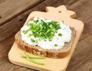Cod liver pate  over brown bread with spring  green onion. Homemade spread made from cod liver, cottage cheese and cut pickles on wooden cutting board.
