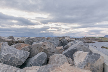 Lighthouse on the Lofoten Islands. Travel to Norway. Norwegian fjords. Huge blocks of stones in the foreground. Photo taken at midnight, midnight sun