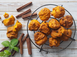 Pumpkin vegetarian or vegan cookies with raisins and cinnamon on a grid on a white wooden background.The view from the top.