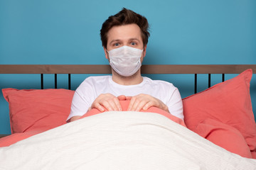Sick mature caucasian man lying down in bed wearing mask protection mask