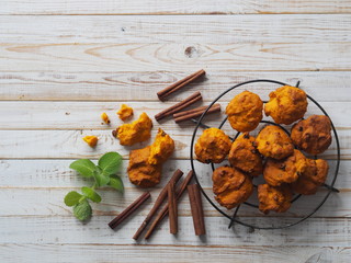 Pumpkin vegetarian or vegan cookies with raisins and cinnamon on a grid on a white wooden background.The view from the top.