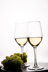 Fototapeta premium Two glasses with white wine and grapes on white background