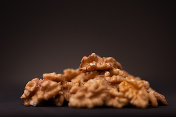 Low key still life of vibrant brown walnut nuts contrasted against a dark studio background with small depth of field