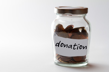 bulbous jar with screw cap filled with coins and the word donation on a label