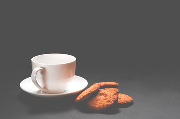 A white cup of coffee with homemade orange biscuits stands on black