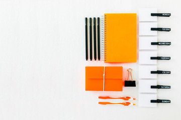 Orange colored office stationery with simple weekday organizer on white background