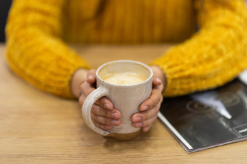 woman hands holding mug of hot drink that standing on wooden table