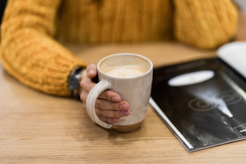 woman hands holding mug of hot drink that standing on wooden table