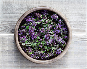 Thyme in a wooden bowl on a wooden table. Flowers thyme collected for drying. Herbal tea thyme. Top...
