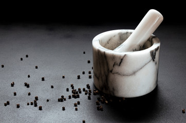 Marble mortar for grinding pepper stands on a black background.