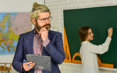 exam or lesson. back to school. modern education concept. teacher and child in classroom. change of duties. thinking bearded man make notes in clipboard. little girl write answer on blackboard