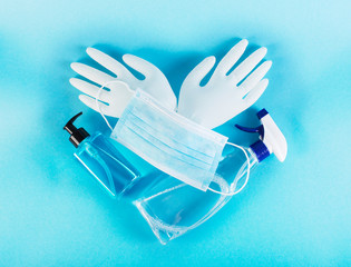 Medical mask, disinfection liquid, soap, latex gloves on blue background. Coronavirus protection...