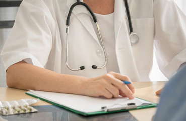 Close up of doctor's hand while sitting in the clinic and give consult to patient . Doctor is writing the chart and explain the symptoms