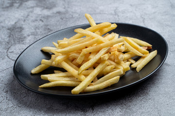 Portion of golden french fries on black plate