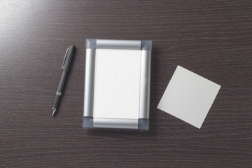 Empty, beautiful, photo frame and empty white paper cards for entries stylish corporate pen on the background of a dark, textured wood table. Empty space. Stylized stock photos. The view from the top.