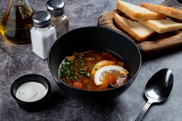 Traditional russian meat hodgepodge soup solyanka on grey stone table