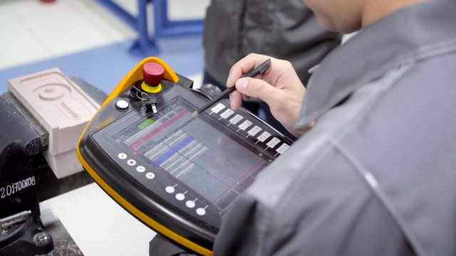 Worker uses touch control panel. Scene. Skilled worker uses electronic control panel in modern enterprise. Close-up of worker setting tasks on electronic control panel