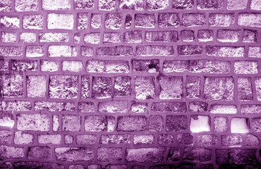 Wall made of old stones in purple tone.
