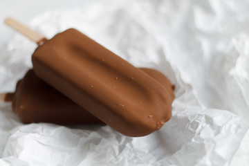 chocolate ice cream on a stick on white paper. summer mood homemade ice cream. making homemade...
