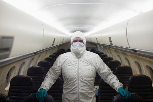 Portrait male worker in clean suit cleaning airplane COVID-19 pandemic