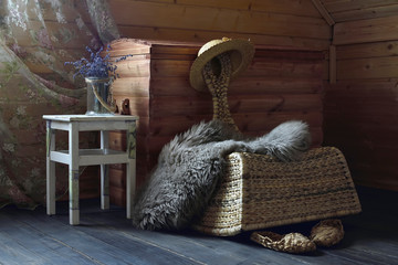A wicker chair, a straw hat, a white stool against a chest.