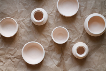 dishes made of white clay without glaze after firing on a brown background close-up. pottery top view