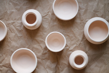dishes made of white clay without glaze after firing on a brown background close-up. pottery top view
