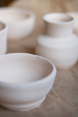 dishes made of white clay without glaze after firing on a brown background close-up. pottery