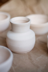 dishes made of white clay without glaze after firing on a brown background close-up. pottery