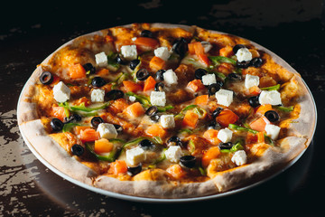 Delicious pizza with olives, feta cheese, pepper and tomatoes. Appetizing food photo.