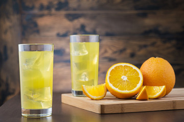 Two full orange juice in glass with ice cubes on wooden background