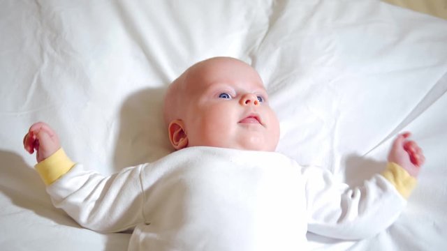 Cute baby smiling and looking at the camera close-up. Little baby with blue eyes in a bodysuit