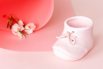 Top view of beautiful fresh crocus and porcelain mug pink baby shoe shape in paper swirl on pastel color background