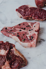 Different types of raw meat for steaks, T-bone, ribeye, fillet, sirloin on a marble desk.