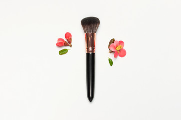Professional makeup brushes with pink spring flowers on light gray background flat lay top view copy space. Beauty product, makeup, women's accessory, fashion. Cosmetic makeup Set