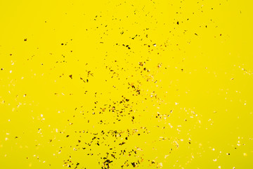 Golden flying sparkles on bright yellow background. Festive backdrop for your projects.
