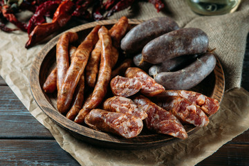 Close-up photo of traditional three kinds of meat sausages in rustic wood bowl on natural black wood table. Perfect man meal.