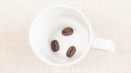  coffee beans spill out of a cup.