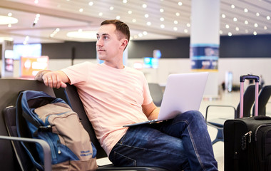 Male businessman European traveler (passenger) with a smartphone and laptop in hand is waiting for departure (flight) at Istanbul Havalimani International Airport (IST Airport)