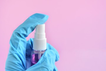 Obraz premium Woman hand in rubber surgical gloves holding antiseptic hand sanitizer on pink background. alcohol sanitizers or gel for hand hygiene corona virus protection. Antibacterial liquid against covid-19
