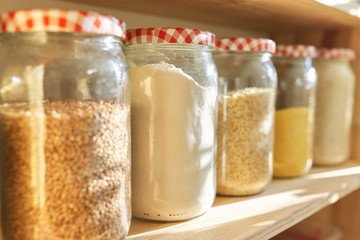 Wooden shelves in pantry for food storage, grain products in storage jars