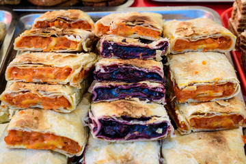 Fresh homemade sour cherries and pumpkin pie pieces displayed for sale at a street food market, side view of healthy food photograph with soft focus