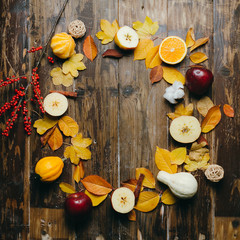 Yellow leaves, apples, pumpkins wreath as a frame at the wooden background. Space for text.