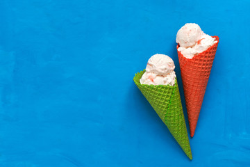 Ice cream in a red and green waffle cone on a blue background, flat lay. Top view, copy space....