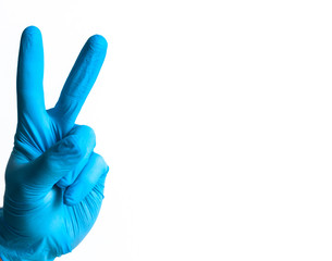 Hand with blue nitrile glove, making the gesture of victory on a neutral background. Positive image...