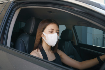 Wome wearing surgical mask in the car, for corona virus or Covid-19 protection.