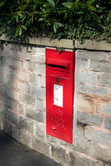 Red postal box in brick wall, UK