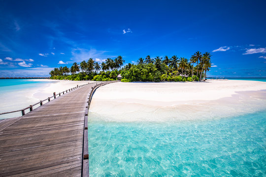 Amazing tropical landscape, beach scenery, long jetty into paradise island. Summer beach view, palm trees on white sandy beach. Tranquil tropical nature
