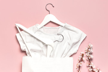 Creative spring sale concept. White wooden hangers with spring flowers white shirt paper bag on...